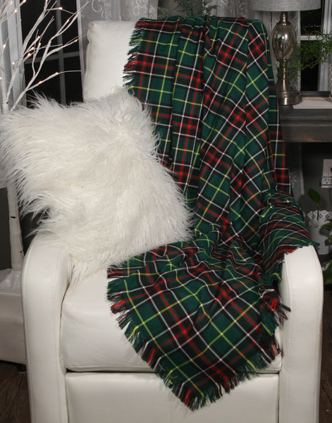 A green and red plaid Newfoundland tartan throw blanket draped over a white chair with a white pillow, in a cozy living room setting.