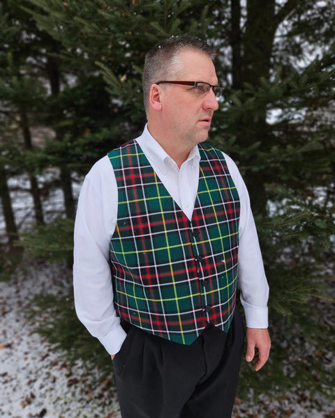 Man wearing a green plaid vest over a white shirt in a snowy forest setting