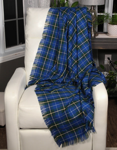 A Nova Scotia tartan blue and yellow plaid throw blanket draped over the arm of a white chair, with a fringed edge visible.