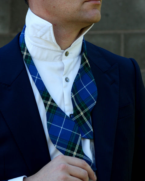 Person wearing a blue and green plaid cravat with a white shirt and dark jacket.