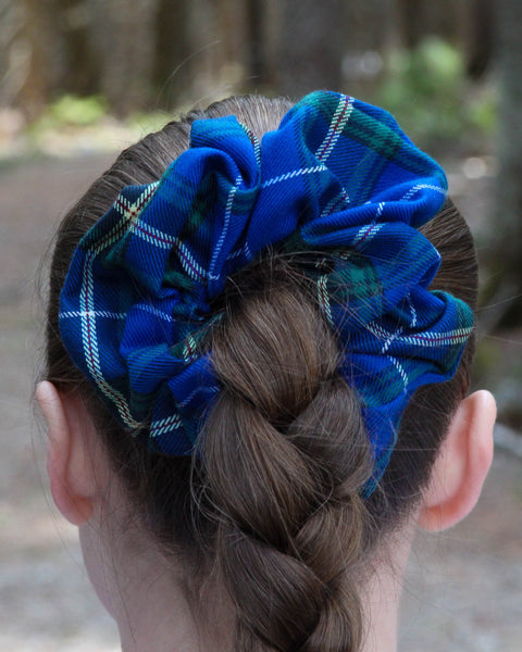 Blue plaid scrunchie on a braided hairstyle with a blurred natural background