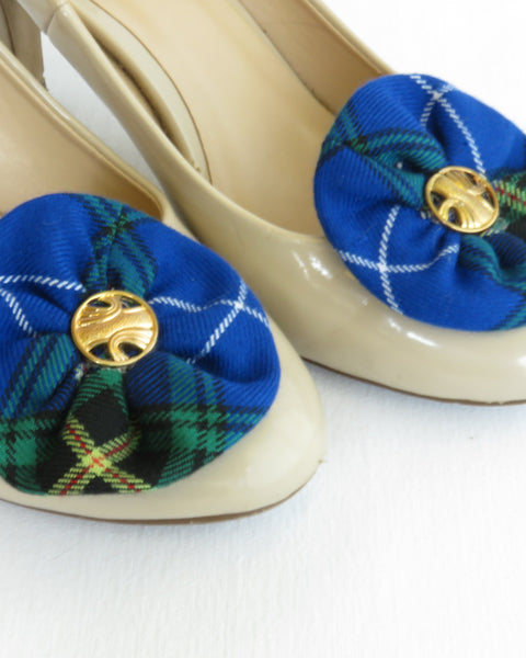 Beige high-heeled shoes with blue tartan flower shoe clips on a white background