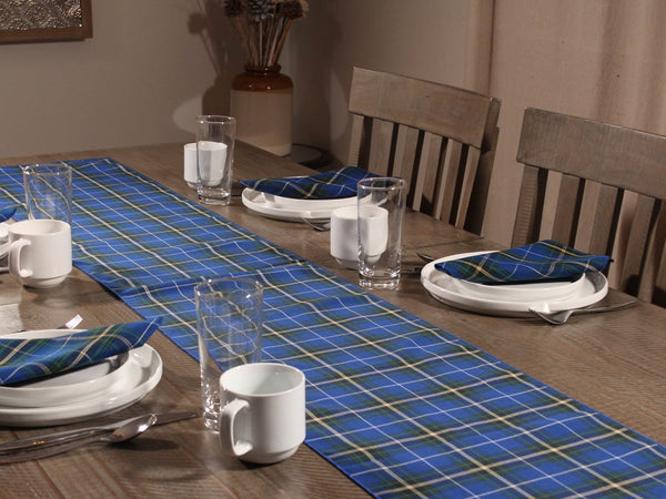Dining table set with blue and white plaid  table runner, white plates, cups, and napkins.
