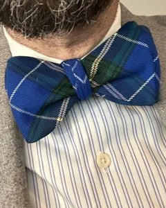 Close up of man with beard wearing a blue and green plaid bow tie with a striped shirt