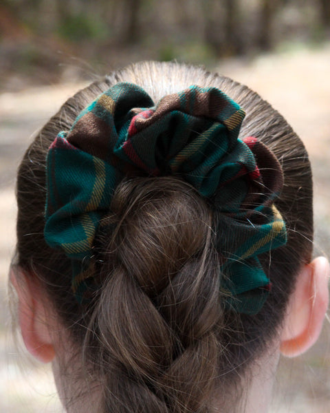 Close-up of a bun with an Ontario tartan plaid scrunchie, blurred natural background