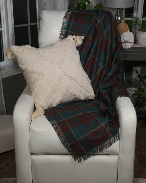 Ontario plaid throw on a white leather chair with a cream fluffy pillow in a cozy room.
