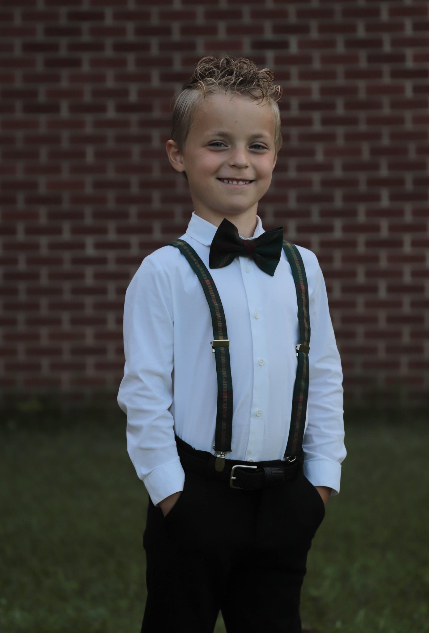 Bioy wearing Ontario tartan red, green, and gold plaid bowtie with matching suspenders and a white shirt and black dress pants.
