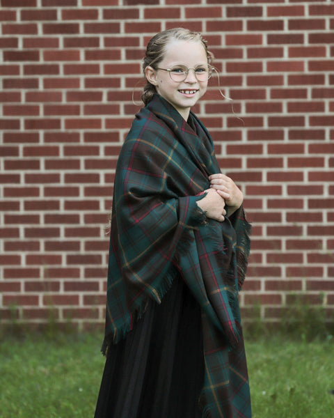 Person wearing an Ontario plaid shawl in front of a brick wall