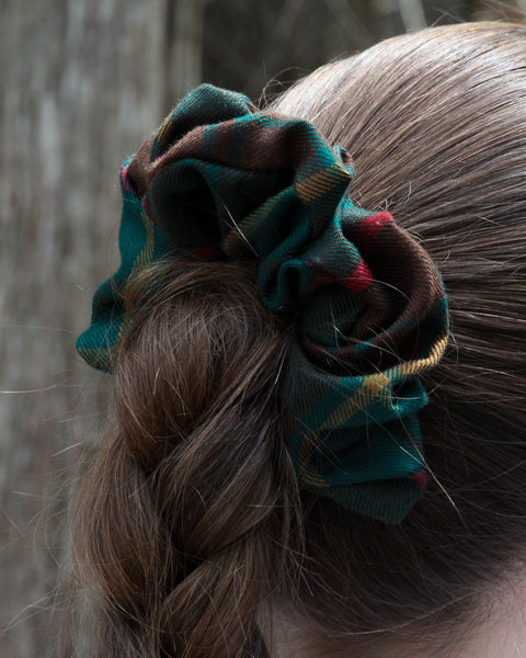 green blue red and gold Plaid scrunchie in a braided hairstyle with a blurred background