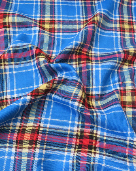 Close-up of blue plaid wool fabric with red, yellow, and white patterns.