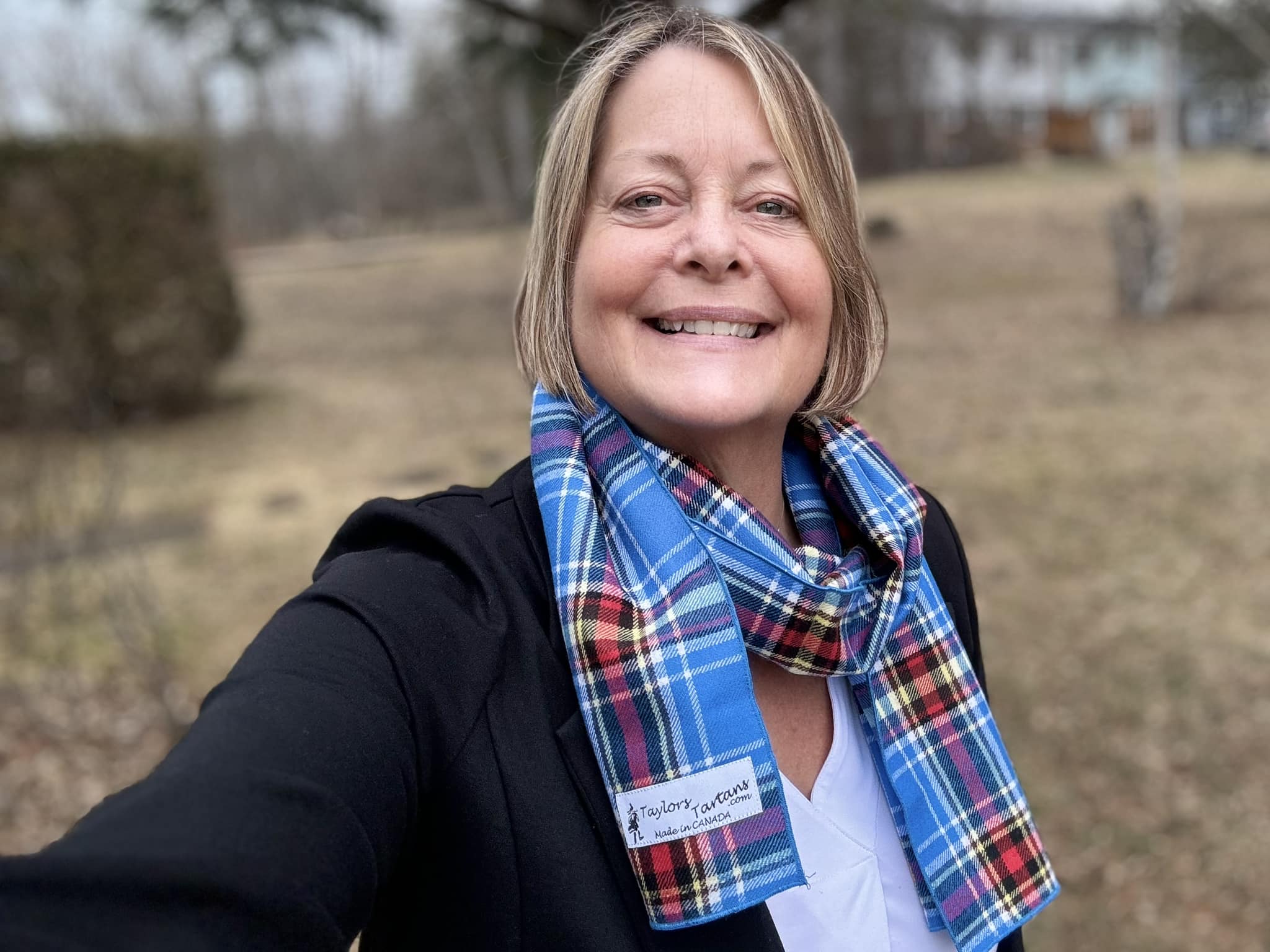woman wearing blue plaid Oromocto tartan scarf looped around her neck