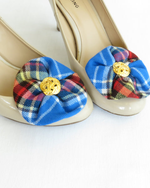 White high-heeled shoes with blue plaid flower shoe clips on a white background