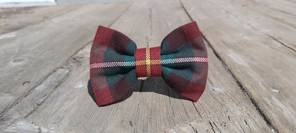 A red and green plaid dog bow tie on a wooden surface.