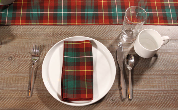 Close-up of a Prince Edward Island plaid napkin on a white plate, with a matching tartan table runner beside.