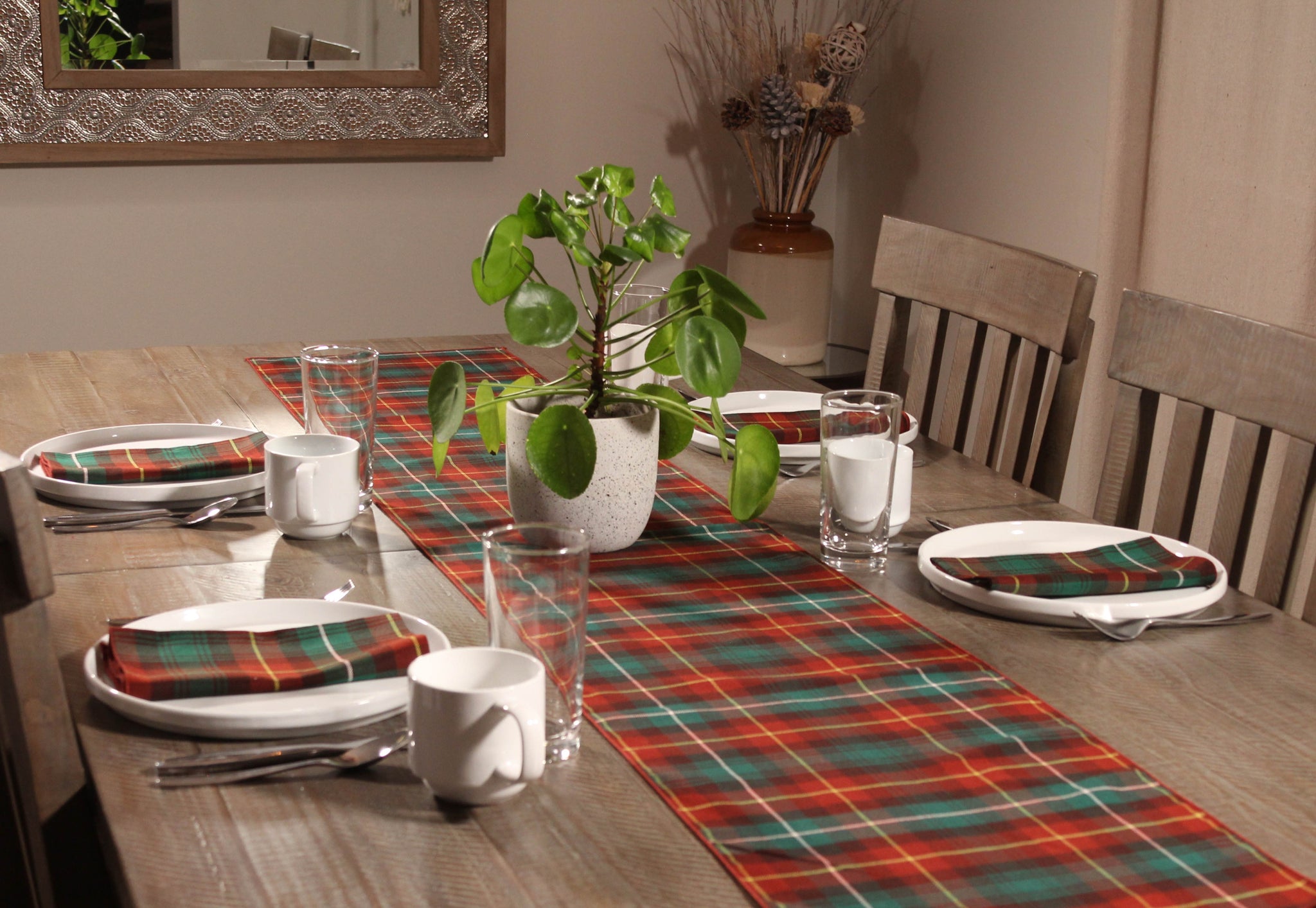 Prince Edward Island tartan table runner on a wooden table, with matching tartan napkins placed on white plates.
