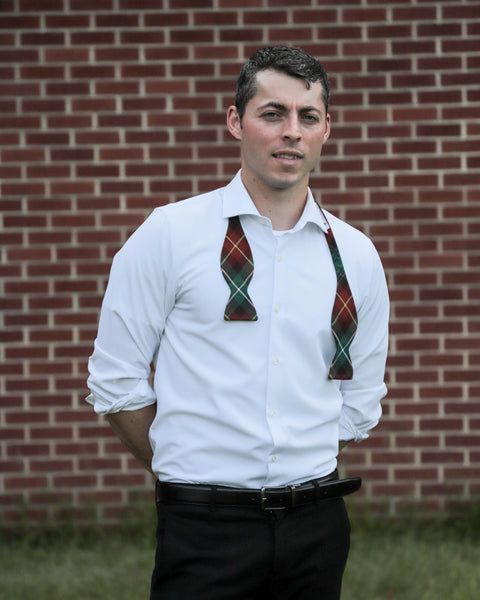 Man wearing untied freestyle bow tie  with a orange and green pattern in front of a brick wall.