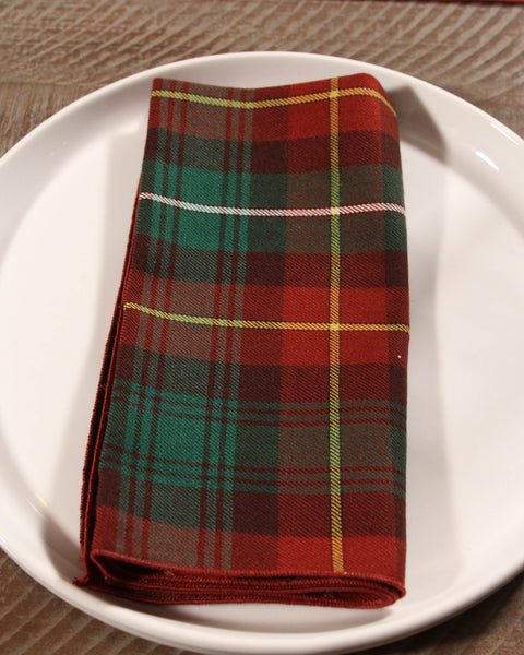 Folded Prince Edward Island plaid napkin on a white plate with a wooden surface background