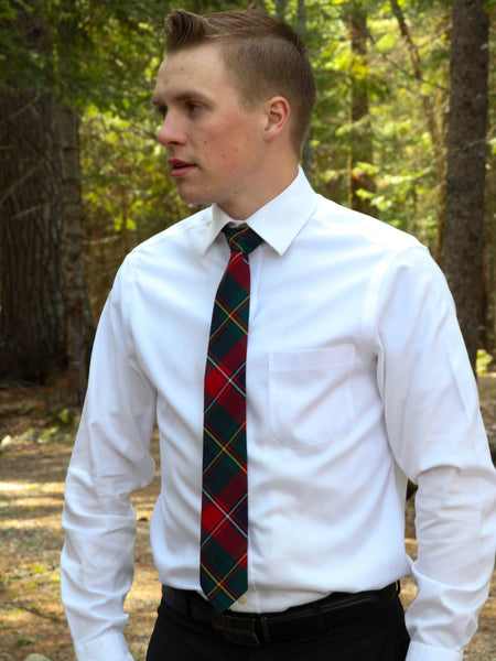 Man wearing a white shirt and red and navy plaid tie in a forest setting