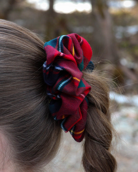Quebec tartan scrunchie in a braided hair against a blurred natural background