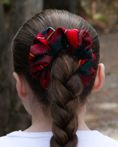 Person with braided hair wearing red and green plaid scrunchies outdoors