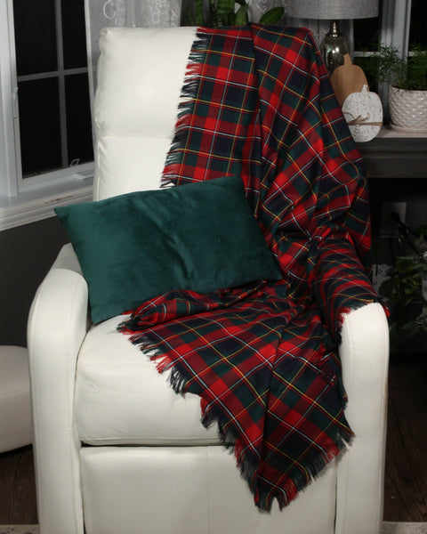 Red and black plaid blanket draped over a white chair with a green pillow.