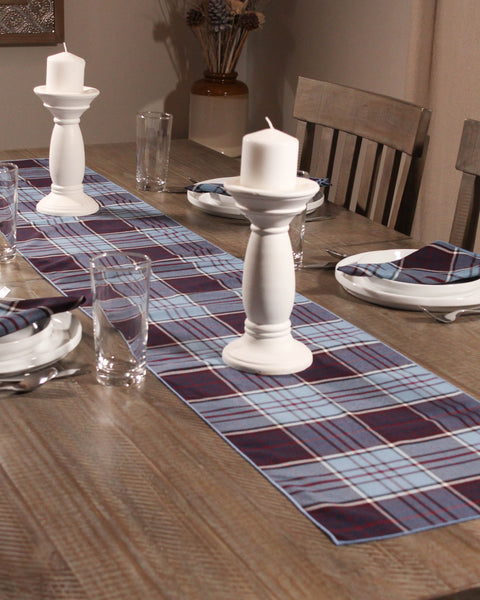 Dining table set with RCAF plaid table runner, candles, and glasses.