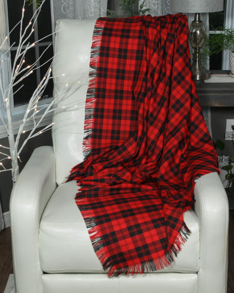 Red and black Menzies plaid blanket draped over a white chair with decorative elements in the background.