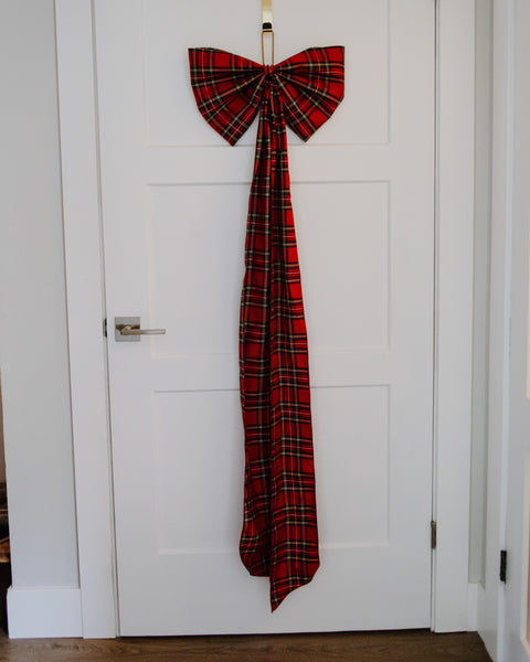 royal stewart tartan red black white and gold plaid over size christmas tree bow on the front of a white door.