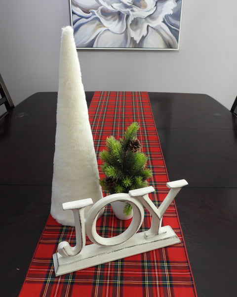 Dark table with red plaid runner, white "joy" sign, white cone and mini christmas tree