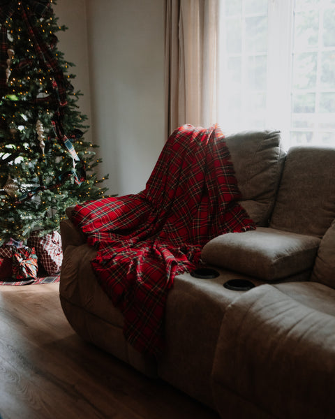 Royal Stewart tartan throw on a couch with a Christmas tree in the backgound