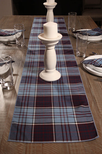 RCAF plaid table runner and matching napkins on a wooden table with white candle holder and glasses.