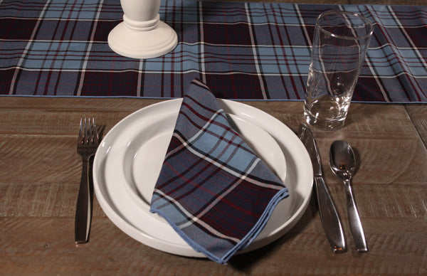 RCAF tartan napkin beside a matching table runner, set on a white dinner plate on a wooden table.