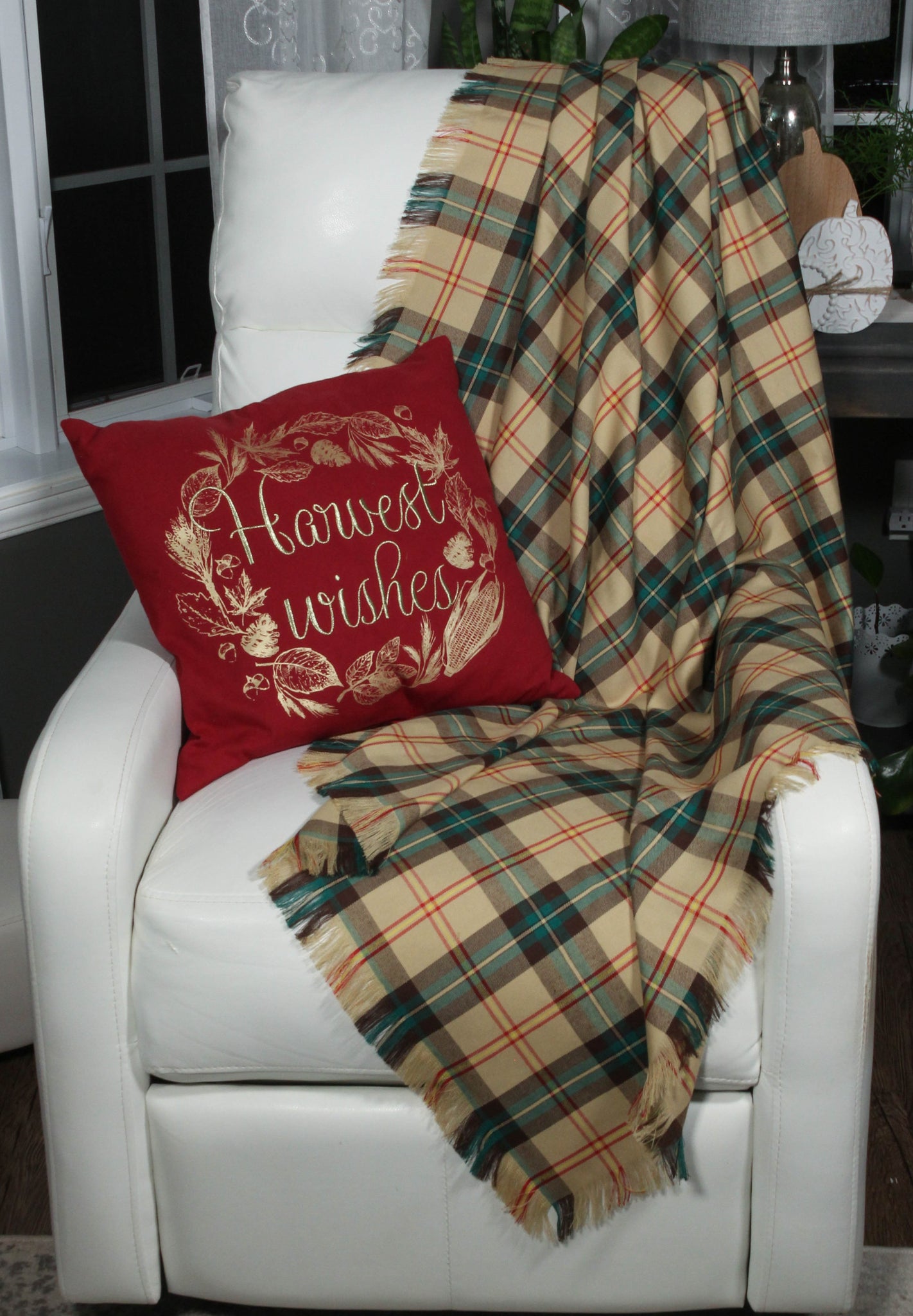 A tan, green and yellow Saskatchewan plaid tartan throw on a white chair with a Christmas pillow.