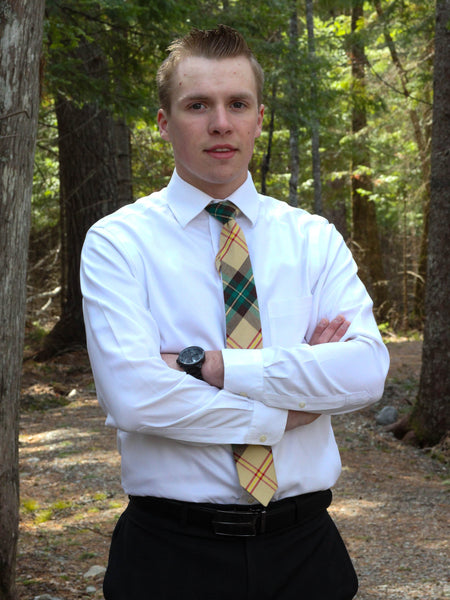 Man wearing a white shirt and yellow plaid tie standing in a forest