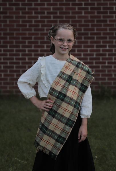 Girl wearing a yellow plaid scarf in front of a brick wall