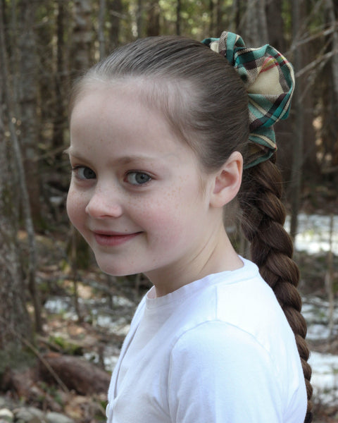 Young girl with braided hair and Saskatchewan plaid scrunchie in a forest setting