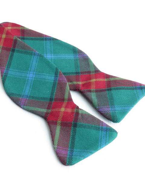 Plaid bow tie with red, green, gold, and black colors on a white background