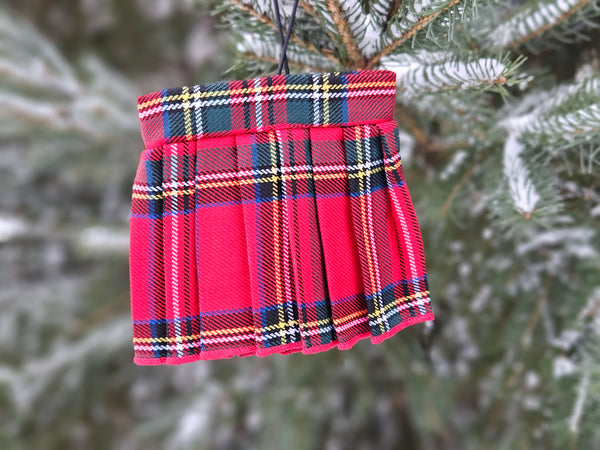 Royal stewart tartan mini kilt hanging on a fur tree branch with snow on it