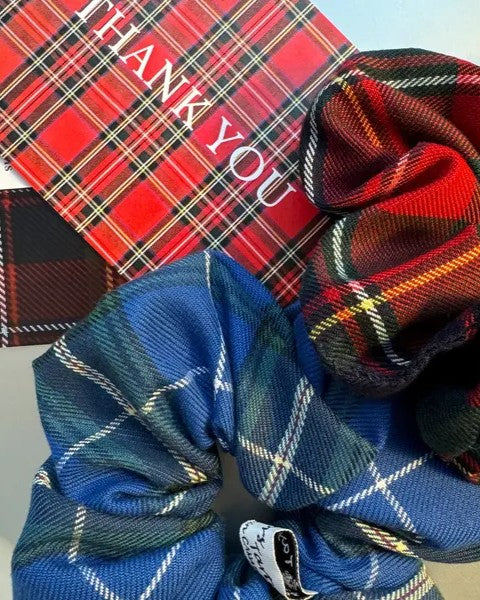 Plaid scrunchies and a red card with 'THANK YOU' text on a light gray background
