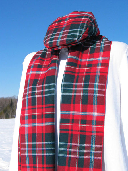 Mannequin in a white dress shirt wearing a red and green plaid hat and scarf. Snowy ground and blue sky in the background.
