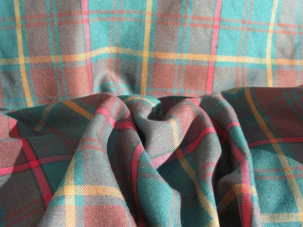 Ontario tartan fabric in green, brown, and yellow tones, scrunched in sunlight to highlight texture and vibrant colors.