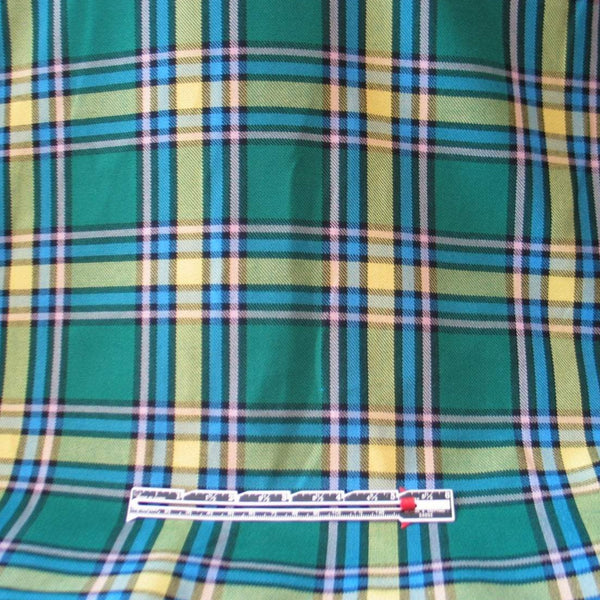 Green, blue, and yellow plaid fabric with a ruler placed to show the size and scale of the tartan pattern.