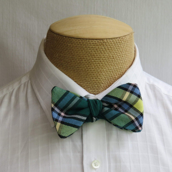 Yellow and green plaid freestyle bow tie styled on a mannequin torso wearing a man's white dress shirt.
