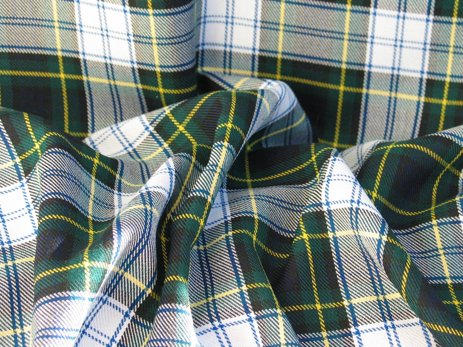 White, navy, and green plaid fabric bunched to show texture. Woven construction makes the pattern identical on both sides.