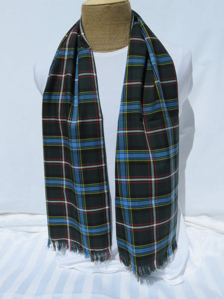 Green and blue plaid scarf with rolled hem sides and fringed ends draped across a mannequin torso, made by Taylors Tartans.