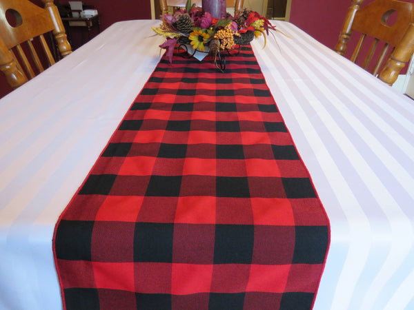 Black and red farmhouse-style Christmas table runner on a white tablecloth.