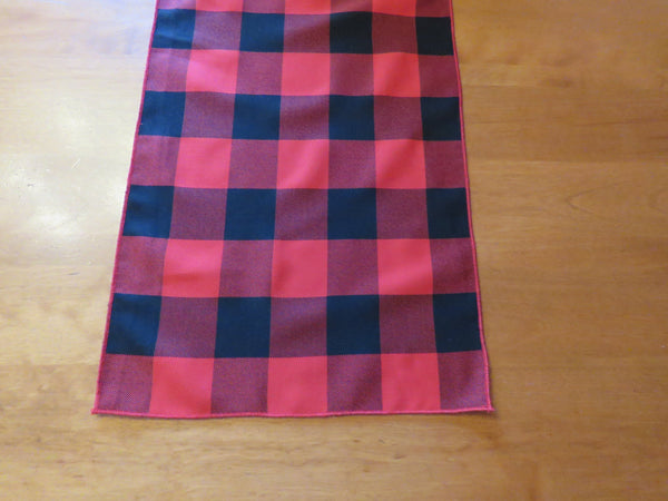 Close-up of red and black buffalo chech table runner on a wooden table.